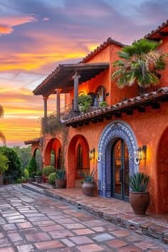 an orange and blue house with potted plants on the front porch at sunset or dawn