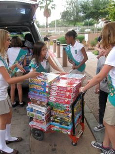 several children are standing around a cart full of books