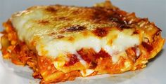 a piece of lasagna on a plate with cheese and sauce all over it