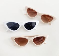 three pairs of cat - eye sunglasses on a white surface