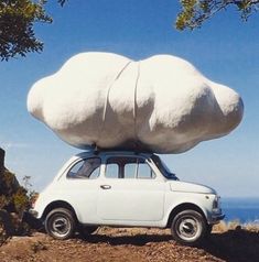 a white car with two large rocks on top of it's roof, parked at the edge of a cliff