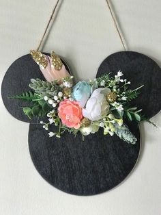 a mickey mouse head with flowers and leaves hanging on a wall or door hanger