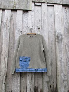 a sweater hanging on a wooden fence with a blue jean pocketed skirt underneath it