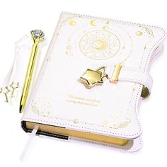 an open notebook with a pen and star charm on the cover, sitting next to it