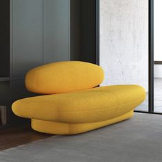 a yellow couch sitting on top of a floor next to a wall with windows in it