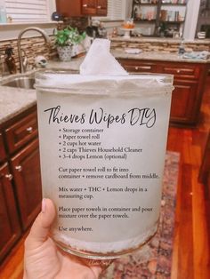 a person holding up a glass with some type of wipes on it in a kitchen