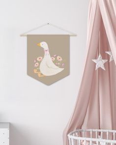 a baby's room with a white crib, pink curtains and a duck hanging on the wall