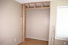 an empty room with some wood framing on the wall and a window in the corner