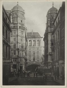 an old black and white photo of people walking on the street in front of buildings