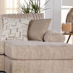 a couch with pillows on it in front of a table and potted palm tree