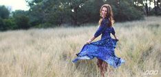 a woman in a blue dress walking through tall grass