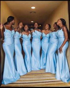 a group of women standing next to each other wearing blue dresses and smiling at the camera