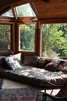 a living room filled with lots of windows next to a window covered in blankets and pillows