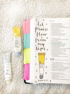 the contents of a beauty book, including lip glosses and sunscreens are laid out on a white carpet