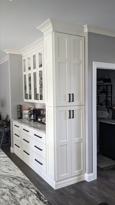 a kitchen with white cabinetry and marble counter tops, along with an area rug on the floor