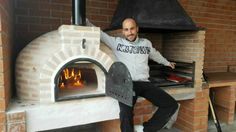 a man is sitting in front of an outdoor brick pizza oven with the door open