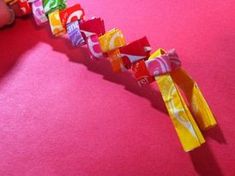 candy bars are lined up on a pink surface with someone's hand reaching for them