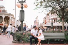 a man and woman are sitting on a bench in front of a street light at disneyland