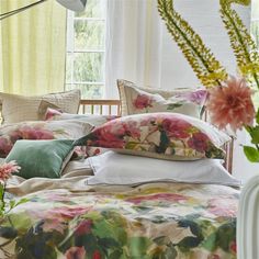 a bed with floral sheets and pillows in front of a window