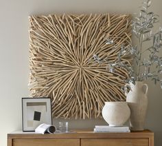 a wooden wall hanging over a dresser next to a vase