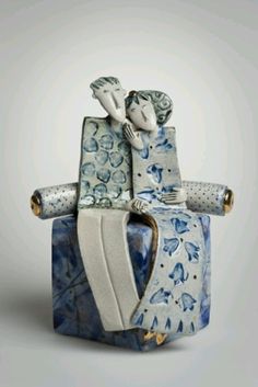 a ceramic figurine sitting on top of a blue and white box with two people in it