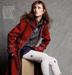 a woman sitting on top of a box wearing white socks and a red coat with buttons