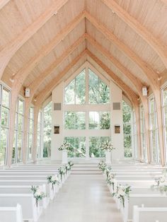 the inside of a church with rows of pews and flower arrangements on each side