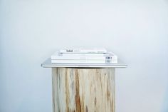 a stack of books sitting on top of a wooden table next to a white wall