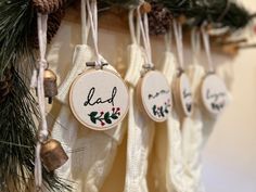 embroidered christmas stockings hanging from hooks with pine cones and evergreen needles in the foreground