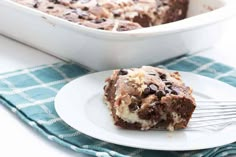 a piece of chocolate chip cake on a plate with a fork next to it and a casserole dish in the background