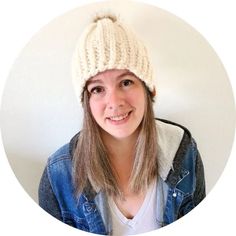 a woman wearing a white knitted hat and denim jacket with her hair in a ponytail