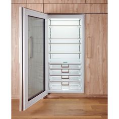 an empty refrigerator with its door open in a room that has wood paneling on the walls