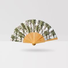 a fan with palm trees on it is sitting in front of a white wallpaper