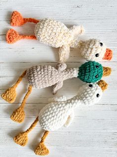 four crocheted stuffed animals are arranged on a white wooden surface with orange and green accents