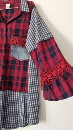 a red and black checkered shirt with lace trims hanging on a white wall