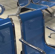 blue seats are lined up in the middle of an empty area with no one sitting on them