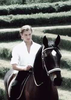 a young man riding on the back of a brown horse in front of mazes