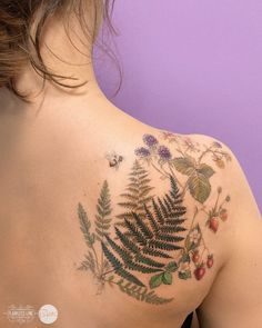 the back of a woman's upper body with tattoos on her shoulder and chest