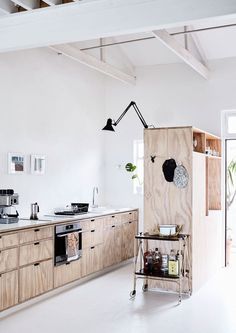 a kitchen with white walls and wooden cabinets in the center, along with an island