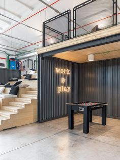 a room with stairs and a foosball table in front of the wall that says work is dilly