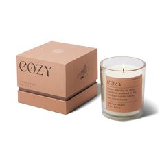 a candle in front of a box with the word cozy on it and an open lid