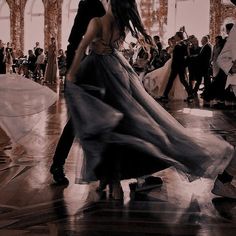 a man and woman dancing in an old building with other people watching them dance on the dancefloor