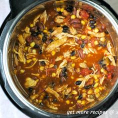 a crock pot filled with chicken, beans and corn