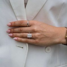 a close up of a person's hand wearing two rings and a suit jacket