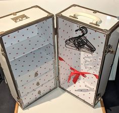 two open suitcases with red bows and clothes pins on them, one opened to show the inside