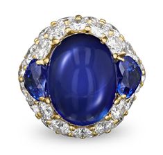 The vivid blue cabochon sapphire that centers this ring totals an impressive 23.78 carats. It is flanked with two additional sapphires which total 4.24 carats and perfectly match the polished cabochon sapphire. The stunning central sapphire suite is haloed with 6.60 carats of sparkling diamonds and set in 18K yellow gold. Sapphire Cabochon, Cabochon Necklace, Jewelry For Sale, Cute Nike Shoes, Cute Nikes, Sapphire Jewelry, Gem Stone, Sparkle Diamonds, Jewelry Lover