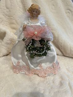 a small angel figurine sitting on top of a white blanket with pink accents