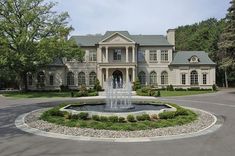 a large house with a fountain in front of it