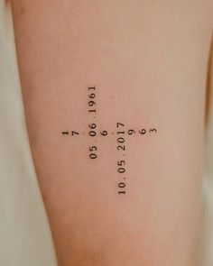 a cross tattoo on the back of a woman's left arm with numbers written in it