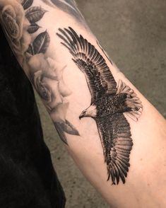 an eagle and roses tattoo on the arm